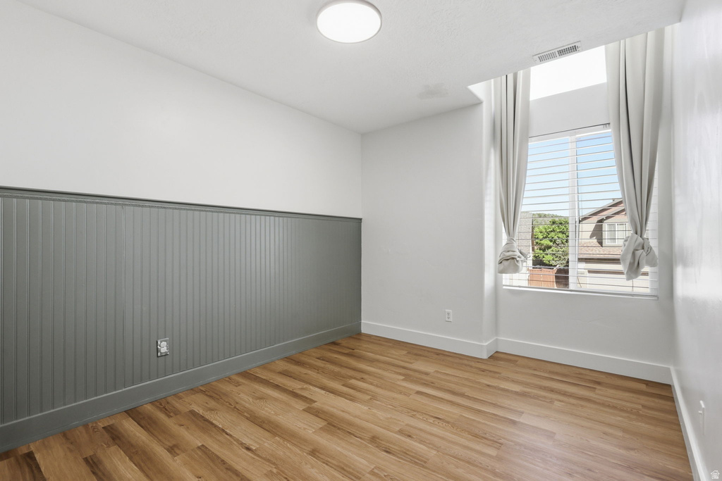 Room with wood-finish flooring, a contemporary ceiling light fixture, and a window with blinds