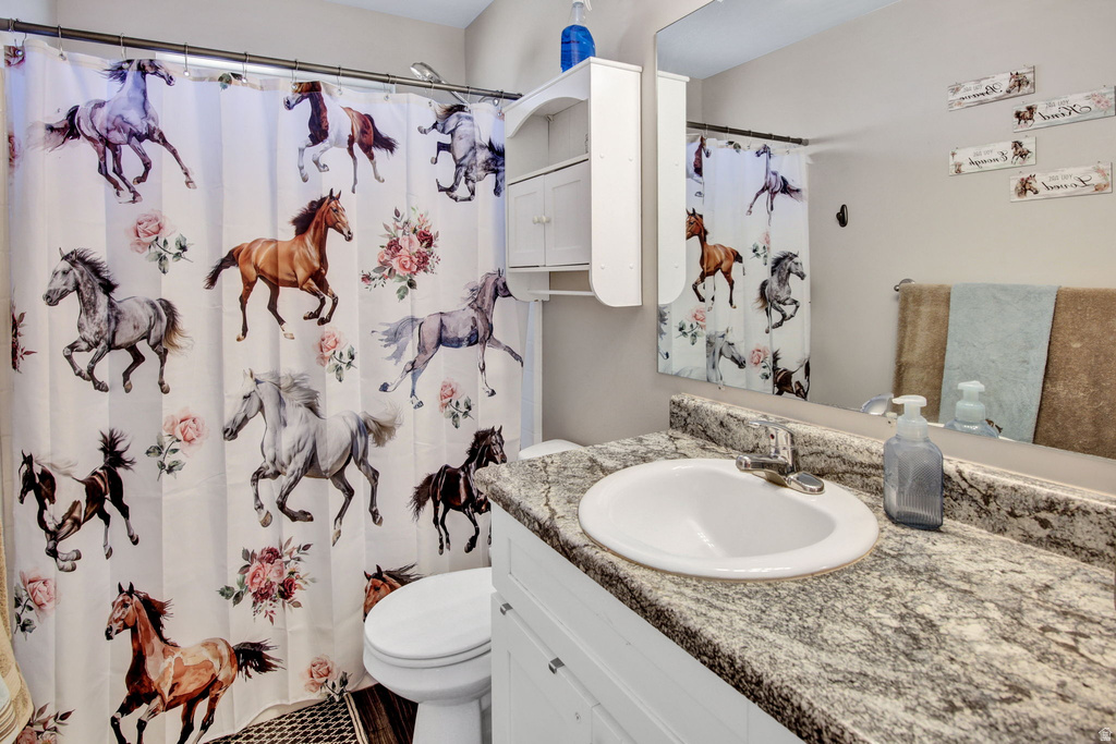 Bathroom featuring a single vanity with a patterned countertop, an undermount sink, and a wall-mounted mirror