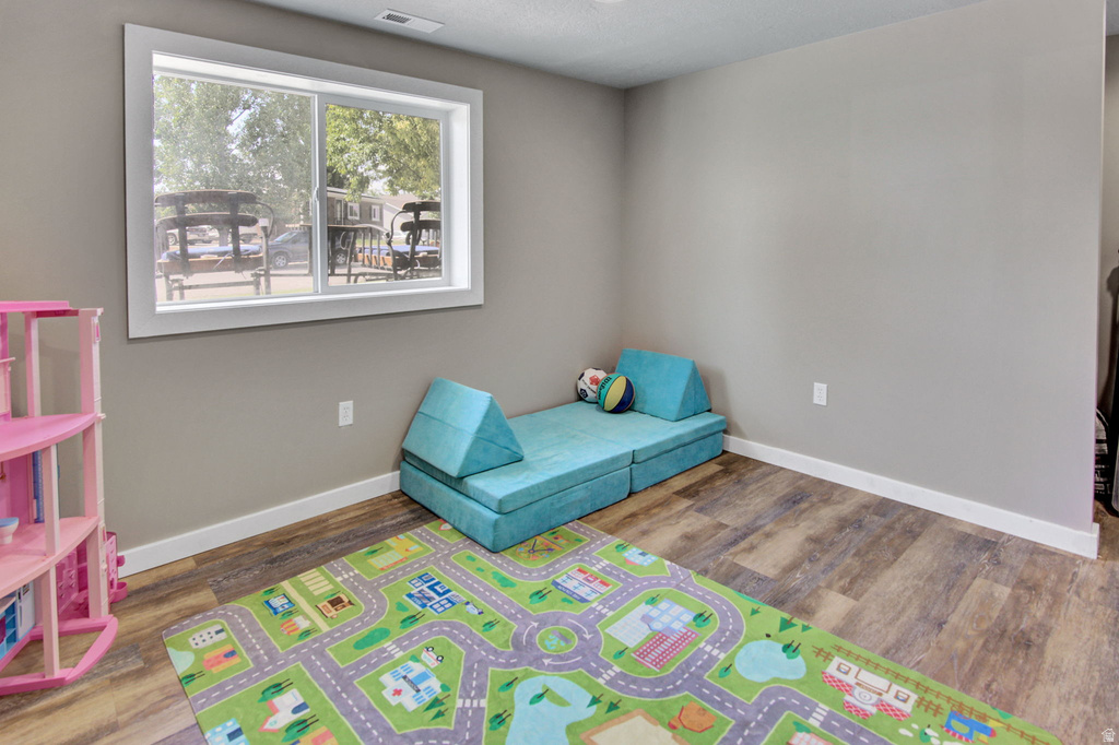 Room featuring a large window with white trim, wood-finish flooring, and light gray walls