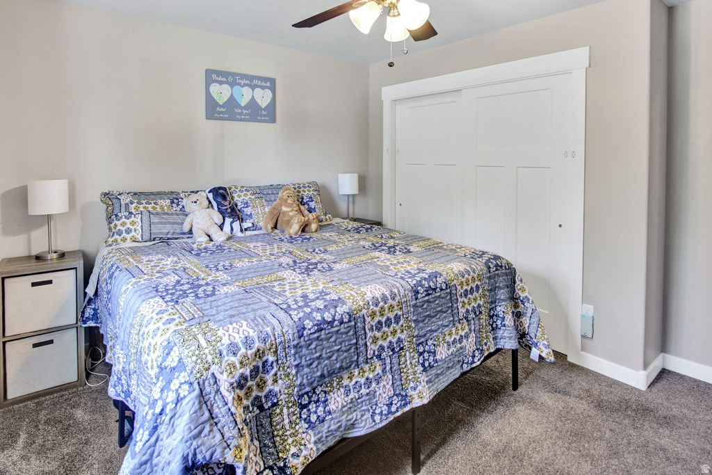 Bedroom featuring neutral wall paint, gray carpet flooring, a ceiling fan with integrated lighting, and a white sliding closet door