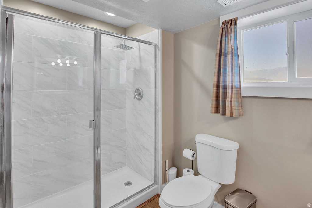 Shower enclosure with clear glass doors, featuring white tiled walls and a rain shower head
