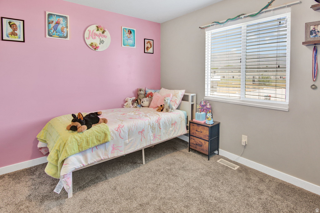 Bright room featuring a large window with horizontal blinds, neutral wall paint, and plush carpeting