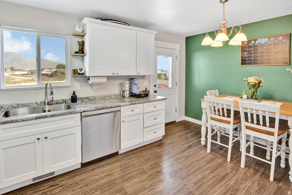 Kitchen and dining area featuring white cabinetry, stone-look countertops, stainless steel appliances, and wood-finish flooring