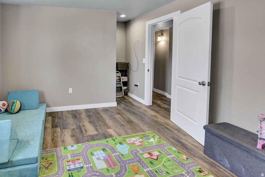 Interior space featuring wood-finish flooring, light-colored walls, white baseboards, and a white interior door with a paneled design