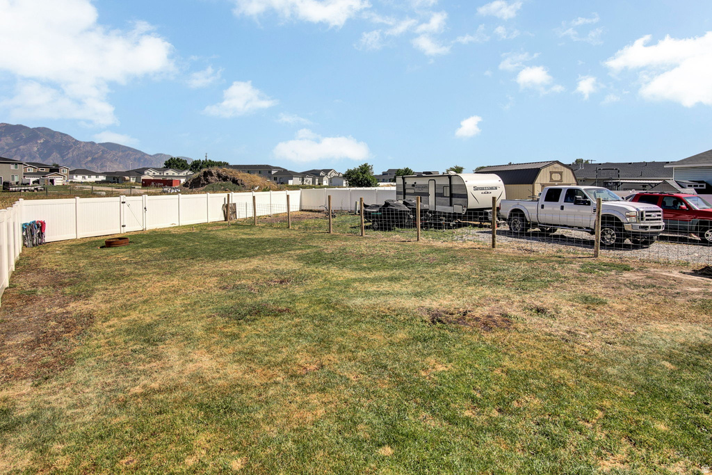 Expansive backyard with privacy fencing, a gate, and a storage shed
