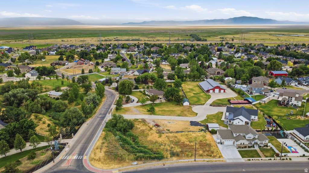 Residential area featuring a paved road, established homes, undeveloped parcels, and distant mountains