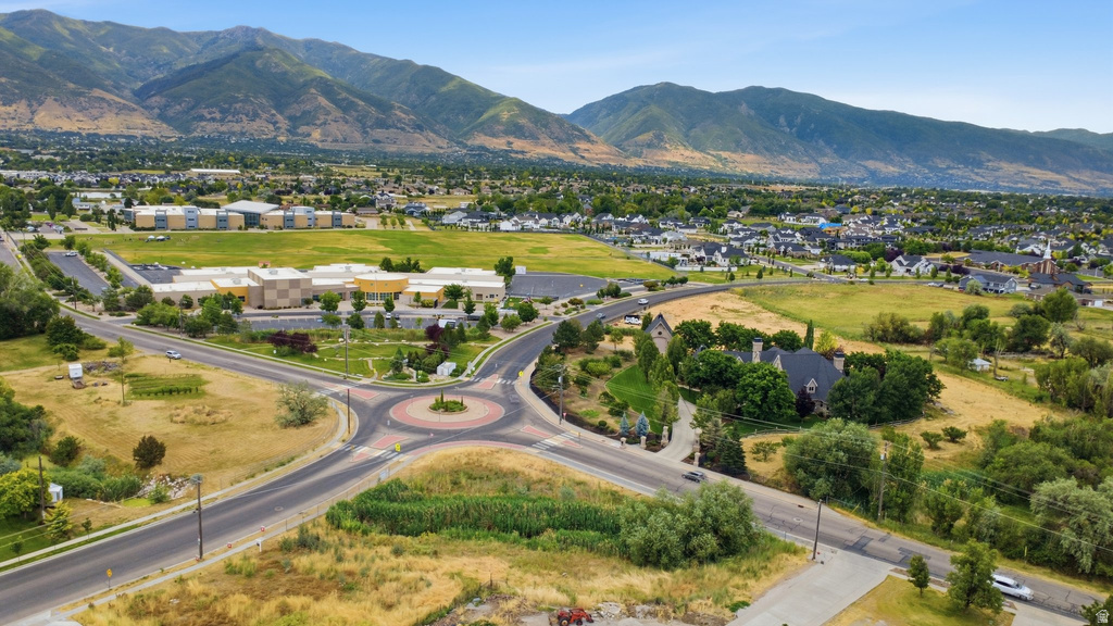 Aerial perspective showcasing a residential area with a prominent roundabout, surrounded by green spaces and distant mountains