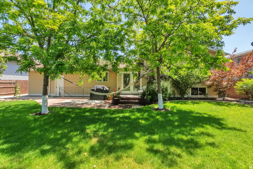 Expansive green lawn framed by mature trees, featuring a brick paver patio and a private fenced yard