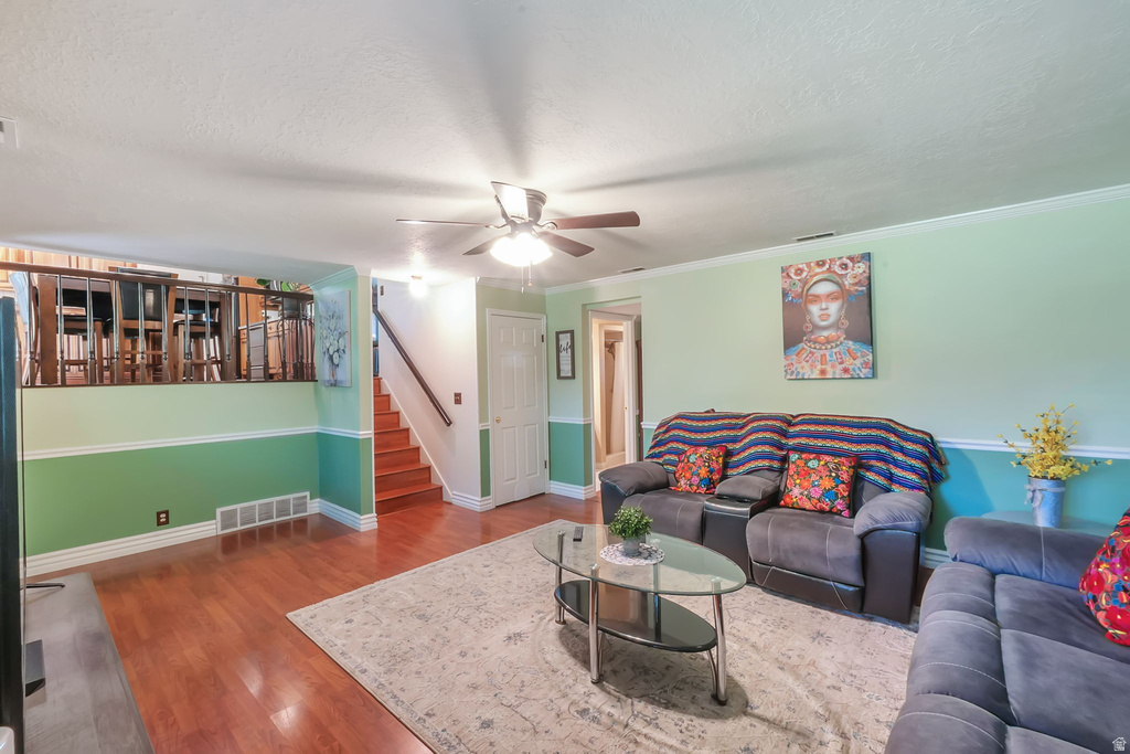 Spacious living area featuring wood-finish flooring, a ceiling fan with integrated lighting, and a partial second-level balcony with wood railing