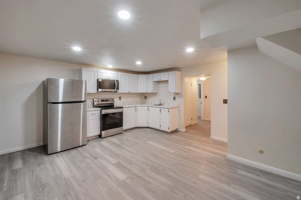 Kitchenette featuring light wood-finish flooring, white cabinetry, stainless steel appliances, and recessed lighting