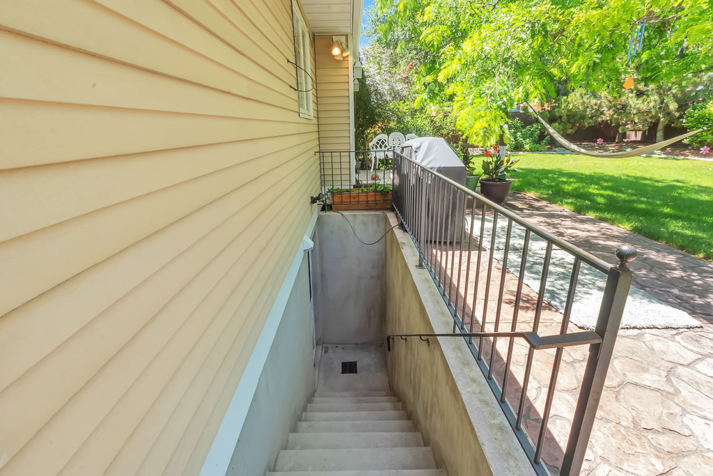Exterior basement entry with concrete steps and metal railings