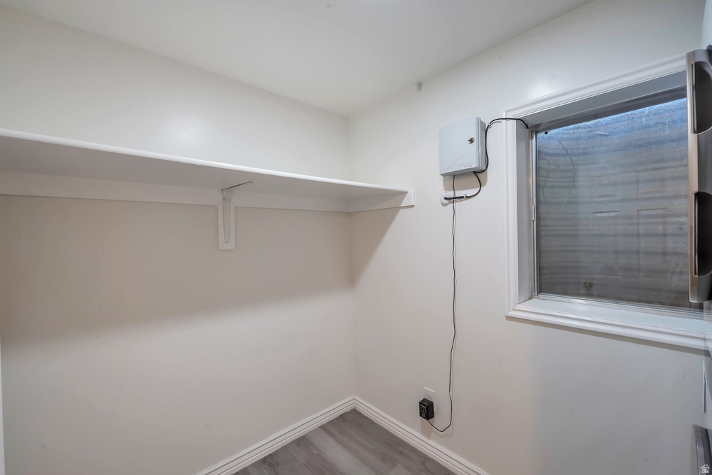 Room featuring a single-pane window, white walls, and wood-finish flooring
