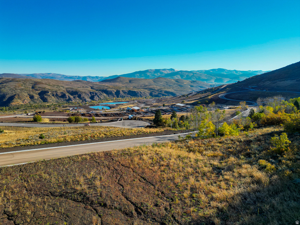 Expansive mountain landscape featuring a winding road, natural bodies of water, and distant structures