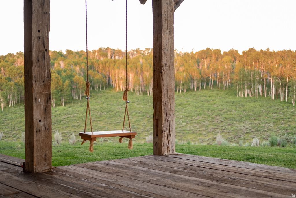 Covered porch featuring a wooden plank floor and rustic wooden support beams
