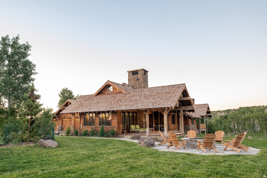 Rustic-style property featuring a cedar shake roof, stone chimney, and expansive wooden siding