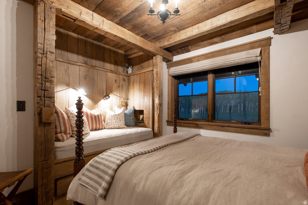 Rustic bedroom featuring exposed wood beams, a built-in daybed with integrated lighting, a wood-framed window, and a wood plank ceiling