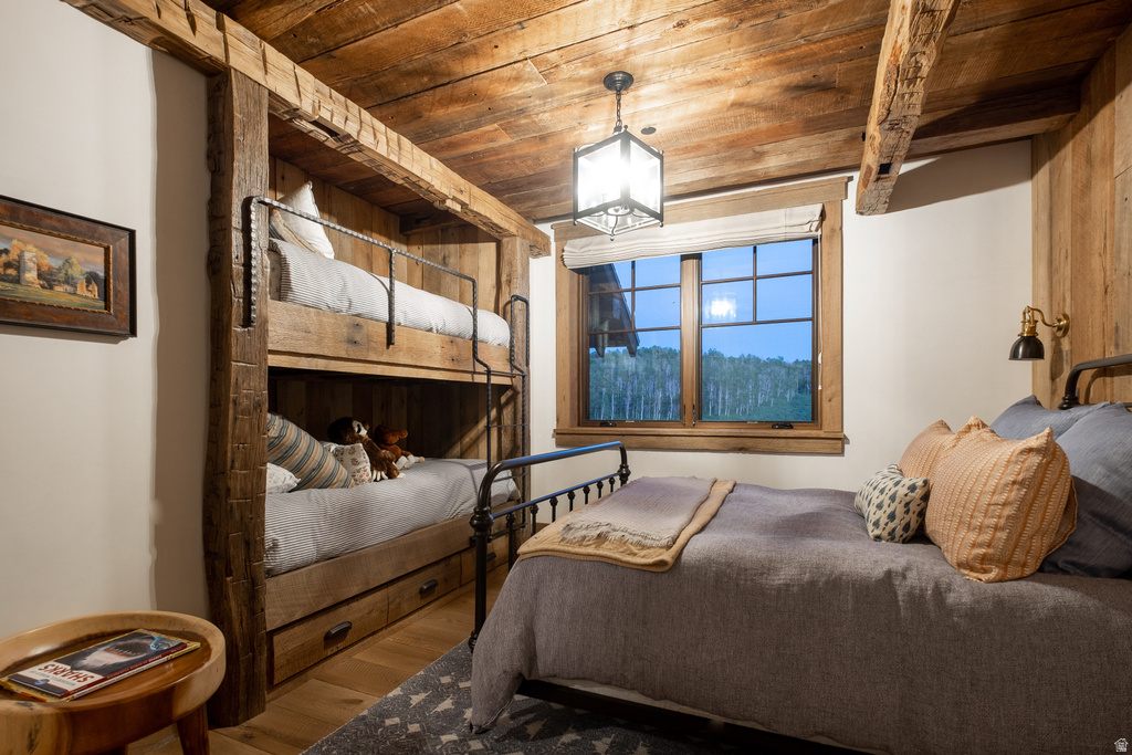 Room featuring a built-in bunk bed system with storage drawers, exposed wood-beam ceiling, and wood-paneled walls