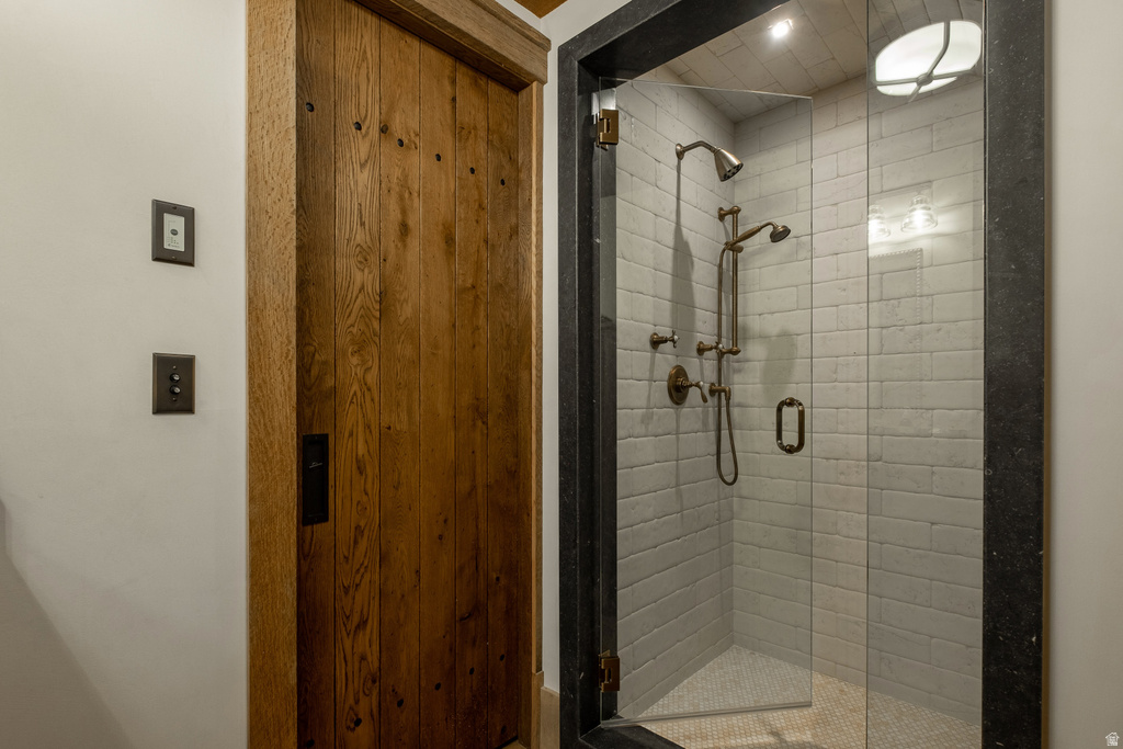 Walk-in shower featuring a frameless glass enclosure, subway tile surround, bronze-finish fixtures, and a pebble tile floor