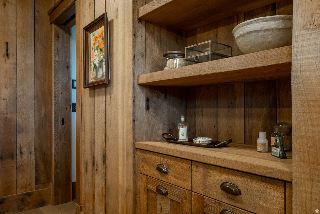 Natural wood plank wall finishes and built-in shelving with integrated drawers featuring distressed bronze hardware