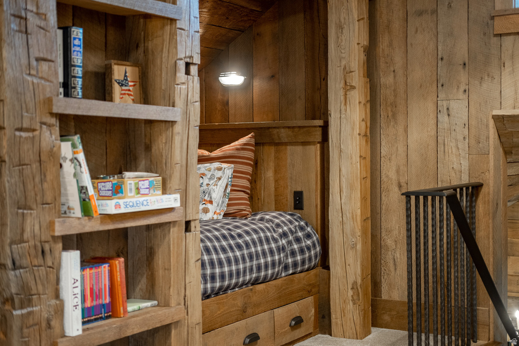 Built-in wood-paneled sleeping nook featuring a wall-mounted light fixture, integrated storage drawers, and adjacent custom shelving