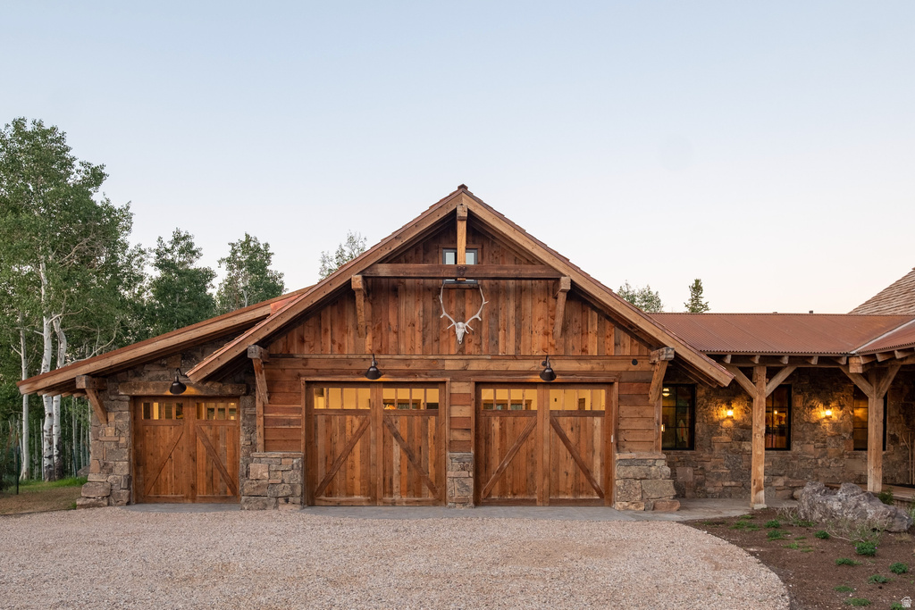 Rustic architectural style featuring a three-car garage with wood-paneled doors and stone accents