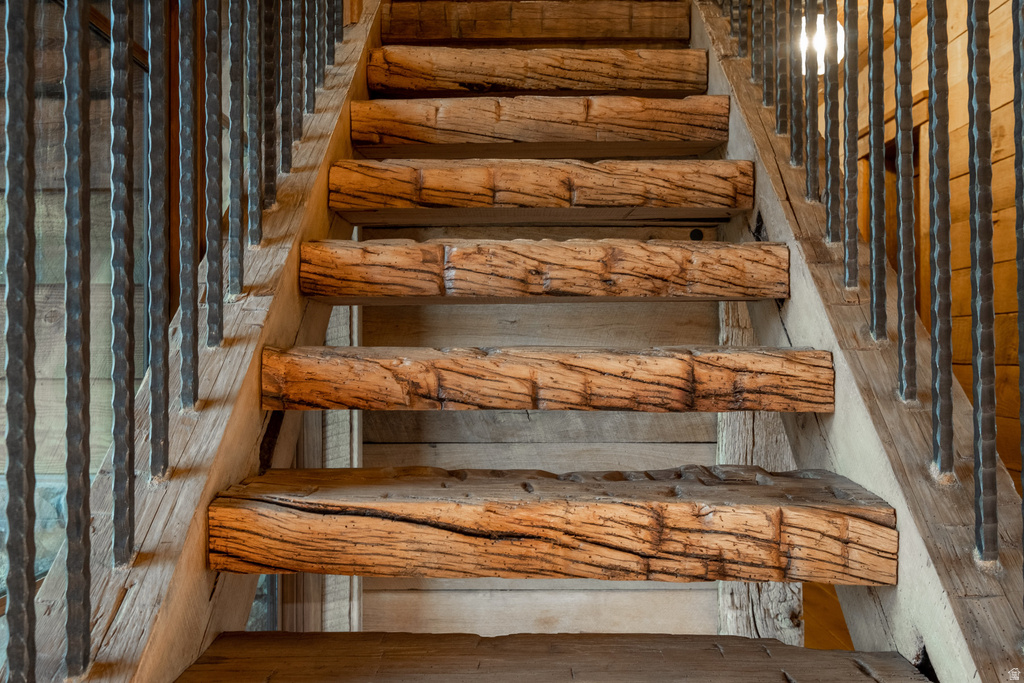 Rustic wood-beam staircase featuring a wood stringer and wrought iron balusters