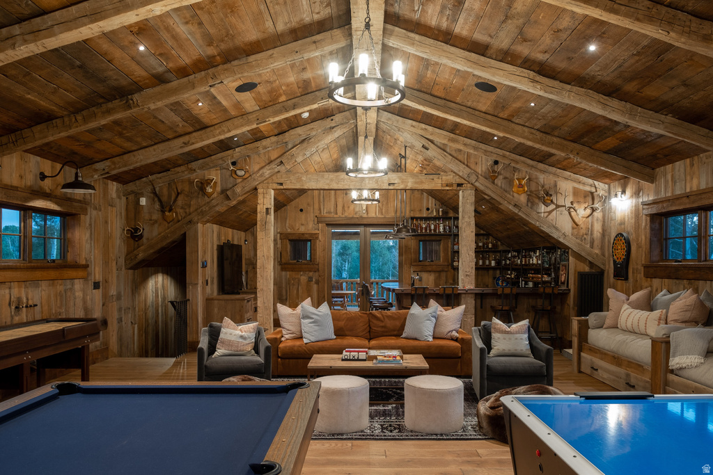 Vaulted wood-paneled ceilings with exposed beams, wood-finish flooring, built-in bar, and multiple windows