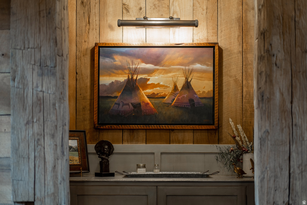 Wood paneling accent wall featuring a picture light, custom cabinetry, and a stone countertop