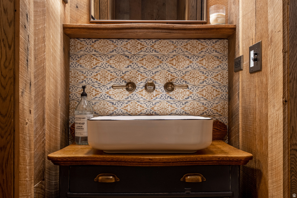 Bathroom vanity featuring a vessel sink, wall-mounted bronze-finish faucet, and patterned backsplash