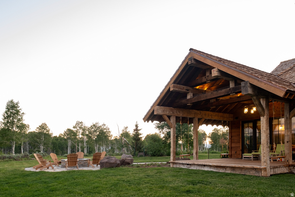 Expansive outdoor living area featuring a covered porch with exposed timber framing and a shingled roof
