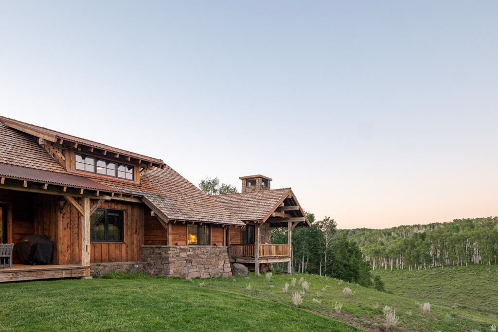 Rustic-style residence featuring natural wood siding, stone foundation accents, a multi-pitched cedar shake roof, and a covered porch
