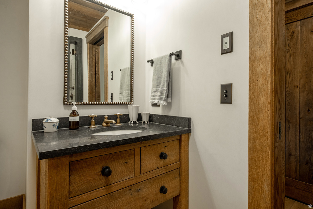Custom wood-finish vanity featuring a dark countertop, an undermount sink, and a decorative mirror