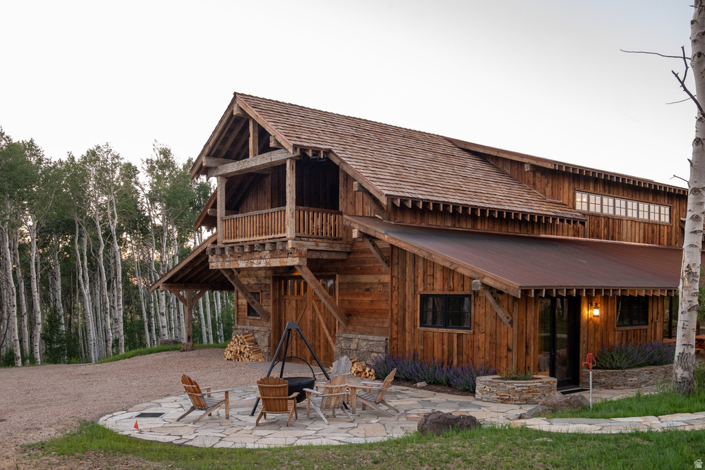 Rustic timber-frame construction featuring a natural wood-shingle roof and a covered metal roof extension