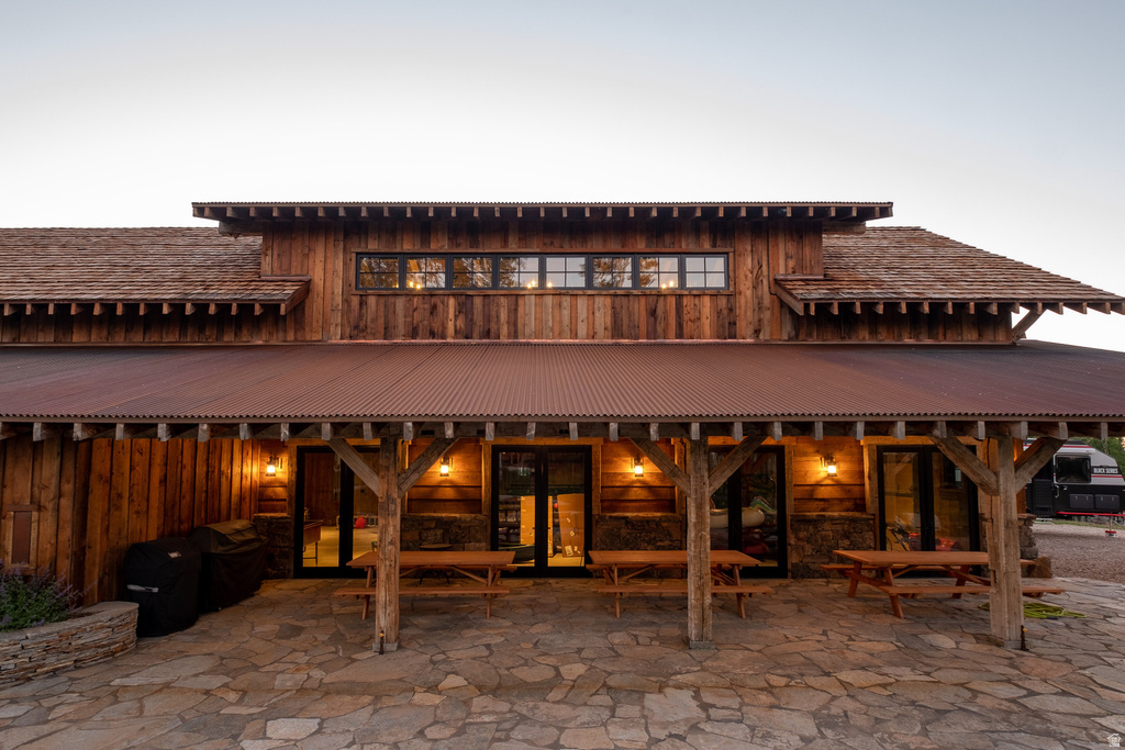 Rustic wood-sided building featuring a corrugated metal roof and a stone patio
