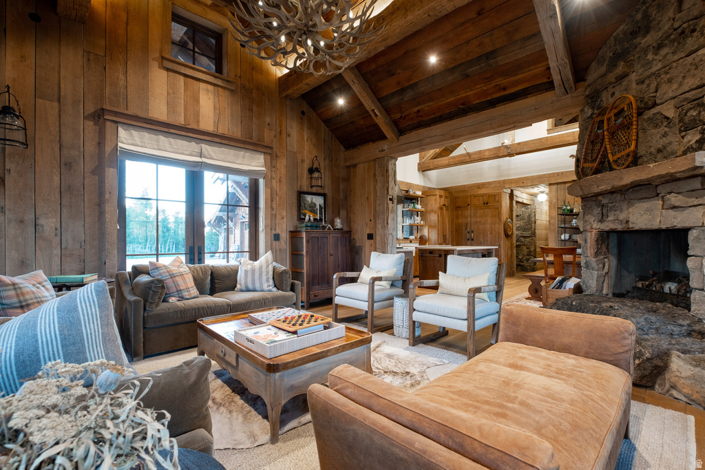 Great room featuring vaulted wood-paneled ceilings with exposed beams, a stone fireplace with a substantial hearth, and a large window with direct exterior access