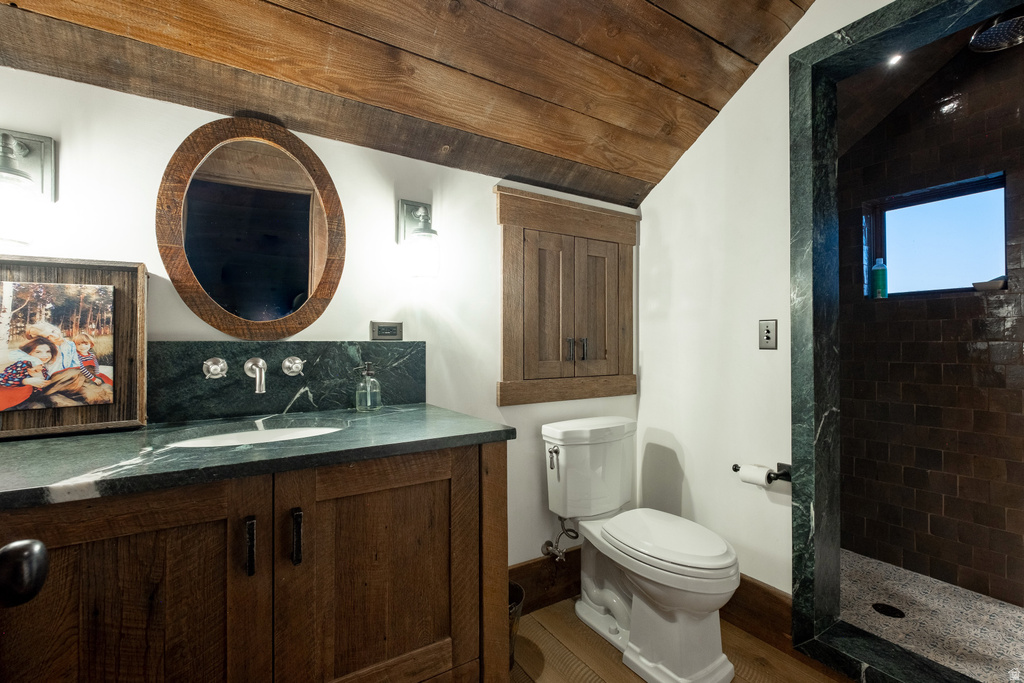 Bathroom featuring a wood-finish vanity with an integrated sink, a dark stone countertop and backsplash, and wall-mounted fixtures