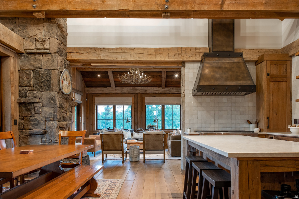 Open-concept interior featuring exposed wood beams, a stone accent wall, and wood-finish flooring