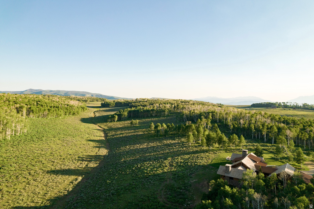 Expansive rural landscape featuring a single-family residence with multiple gables and dormers, surrounded by abundant mature trees and rolling hills