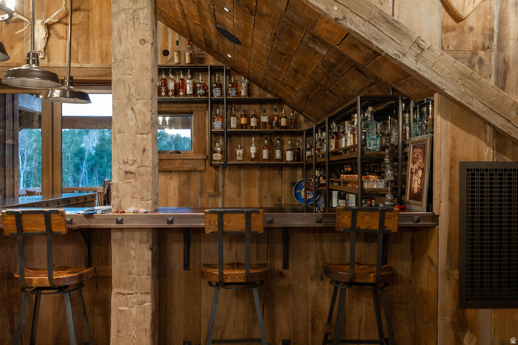 Custom-built bar with integrated shelving and storage, featuring rustic wood paneling and exposed beam ceiling