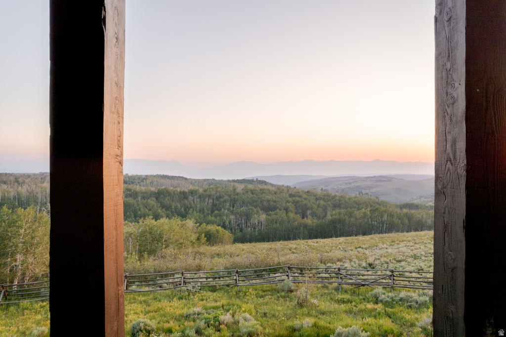 Expansive natural landscape with rolling hills, a lush green field, and dense forestation