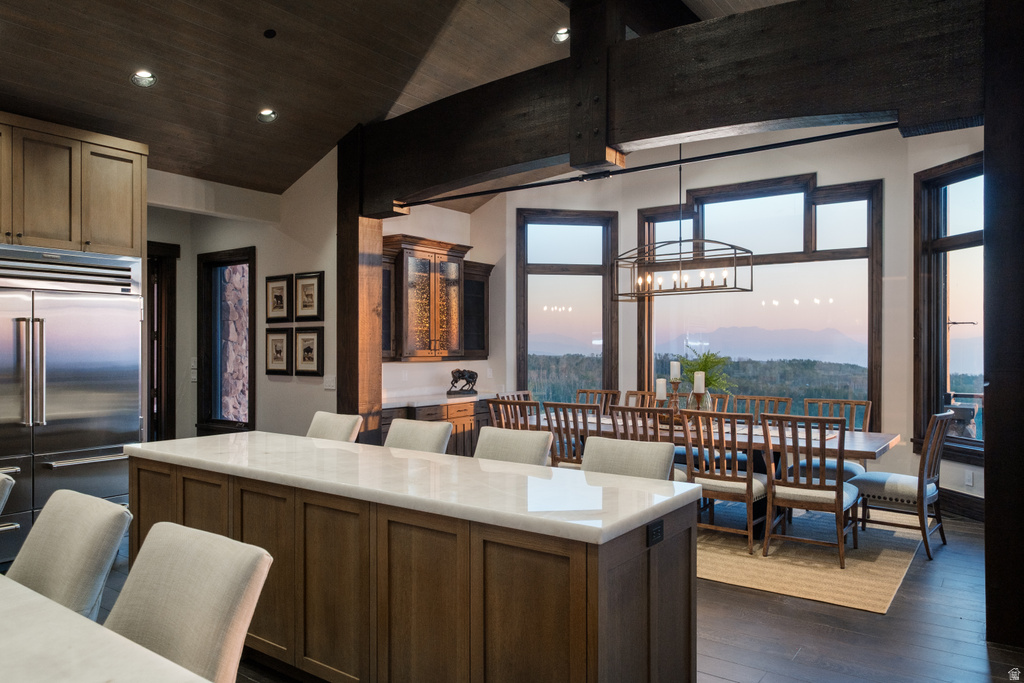 Gourmet kitchen with an expansive island, stainless steel refrigerator, and wood-finish cabinetry