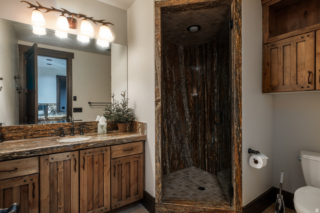 Bathroom featuring a custom wood-look shower enclosure with a tiled floor, a vanity with a stone countertop, a single basin sink, and wood-finish cabinetry