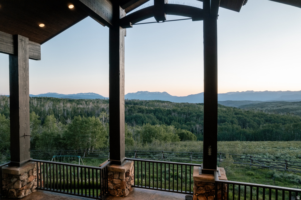 Spacious covered deck featuring substantial timber columns with stone bases and metal railings