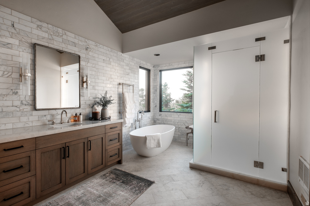 Spacious bathroom featuring a freestanding soaking tub, large window, frosted glass shower enclosure, wood-finish vanity with a stone countertop, and marble-style subway tile walls