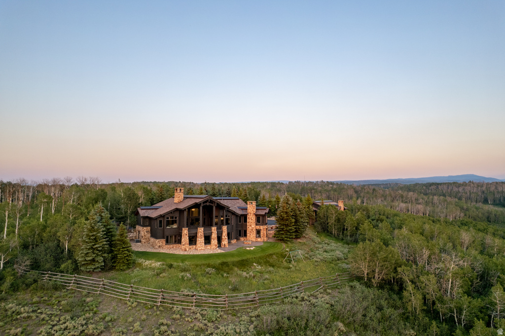 Expansive property featuring a multi-level residence with stone and dark wood siding, multiple chimneys, and a stone retaining wall