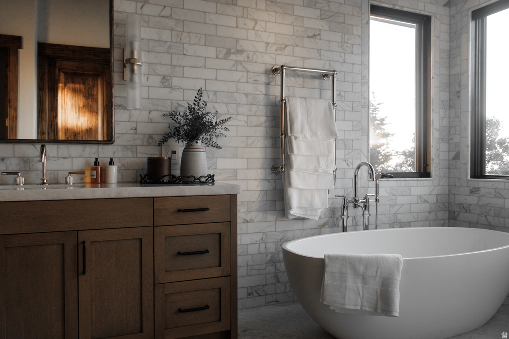 Freestanding soaking tub with floor-mounted faucet, complemented by a wood-finish vanity with a light-toned countertop and dual windows