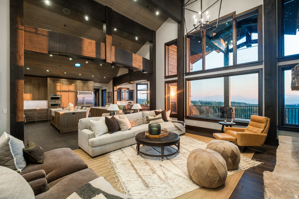 Open concept living space featuring a two-story ceiling, exposed wood beams, and dark wood-finish flooring