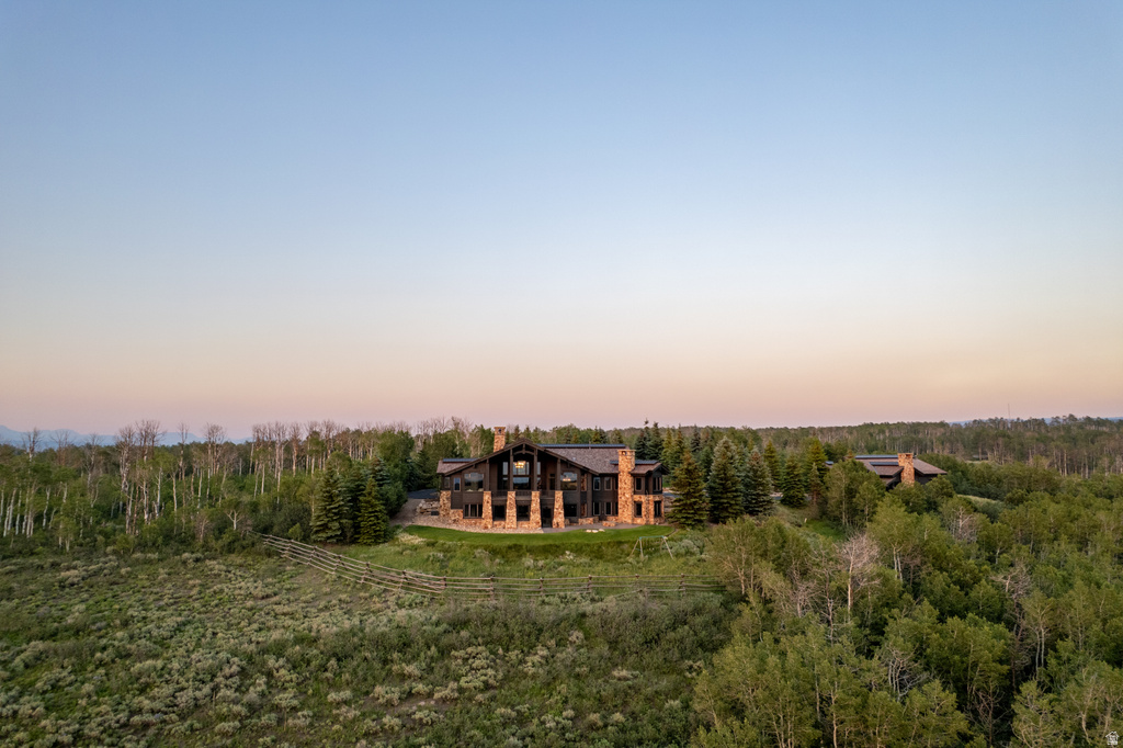 Stone and timber residence featuring multiple chimneys, a multi-story window facade, and a stone patio