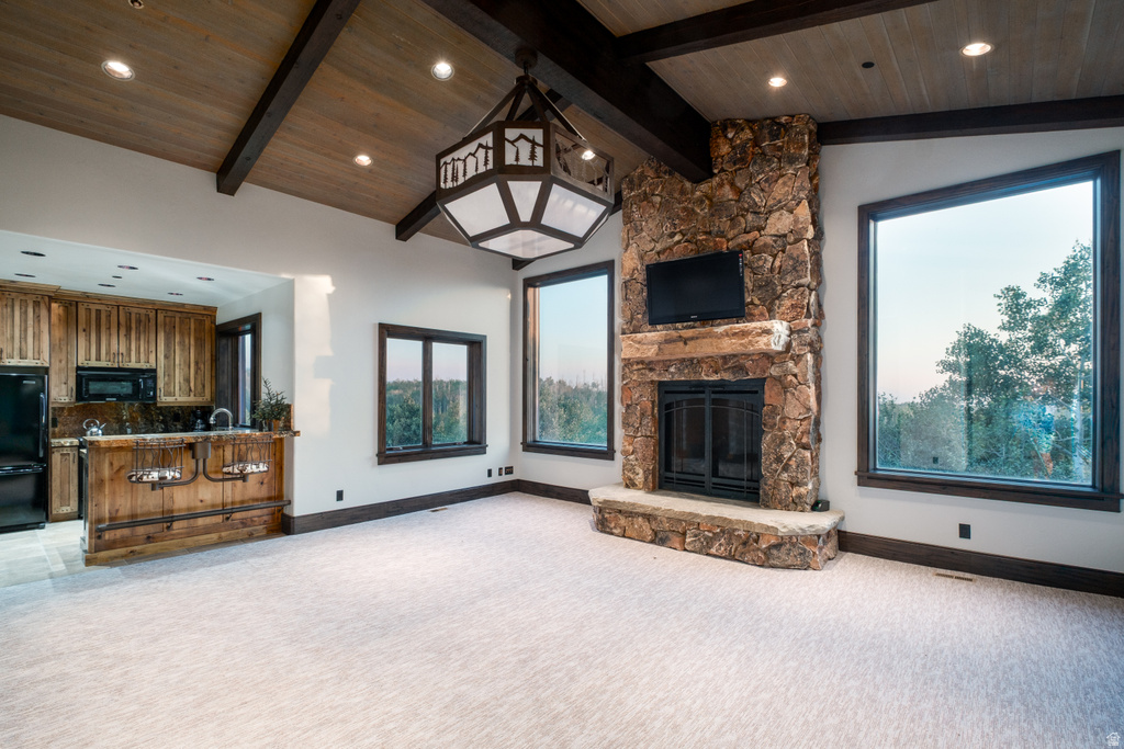 Great room featuring a prominent stone fireplace, vaulted wood-paneled ceiling with exposed beams, and a built-in wet bar with wood cabinetry and a dark countertop