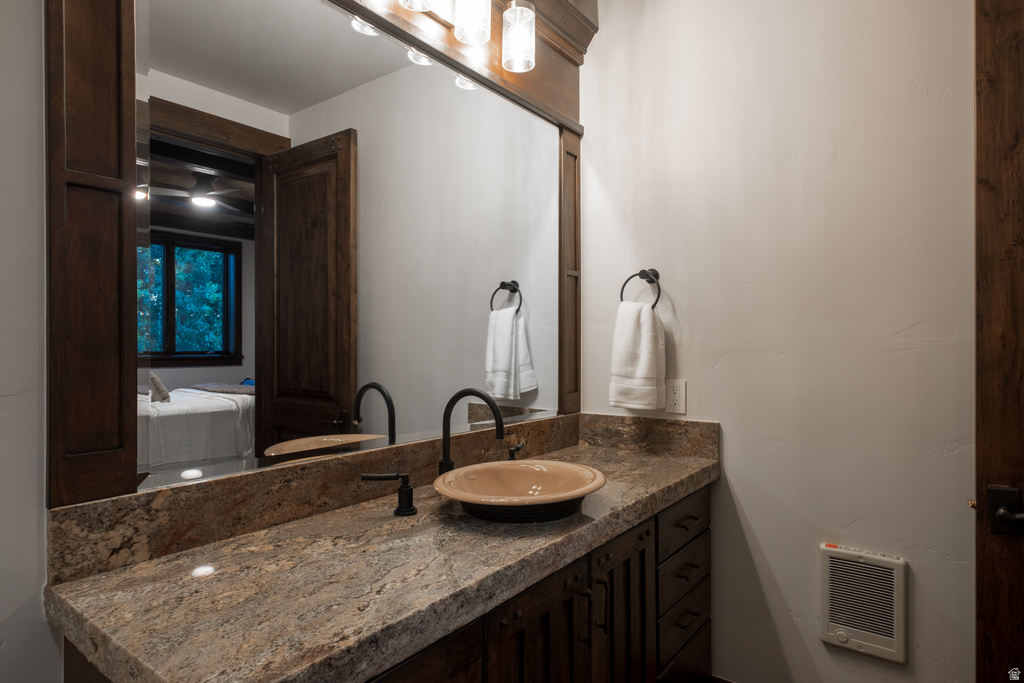 Bathroom vanity featuring a stone-finish countertop, a bowl sink, and a wall-mounted faucet